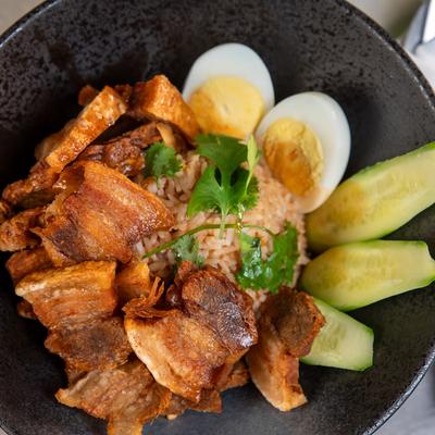 Fried pork belly, red sauce, cucumbers, boiled egg, and cilantro over rice.