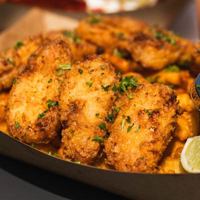 Chicken Tenders served over fries with lime wedges, close-up.