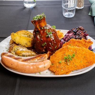 A sampler plate with various meats and potatoes.