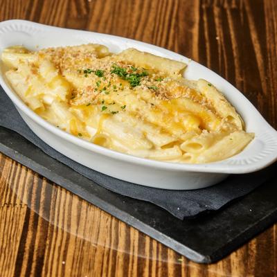 Baked macaroni and cheese in white dish on a wooden table.