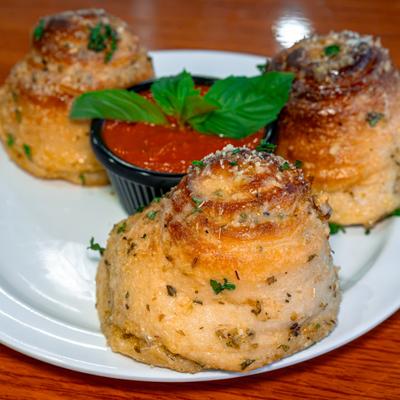 Garlic knots arranged around marinara sauce.
