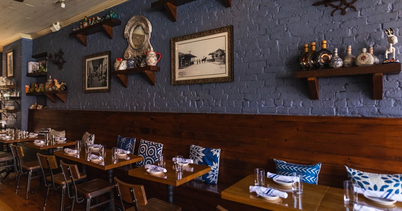 Interior seating area with wooden shelves with decorative items, wooden tables and colorful cushions