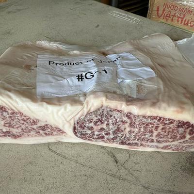 A large cut of marbled beef wrapped in plastic, labeled Product of Japan, rests on a gray surface.
