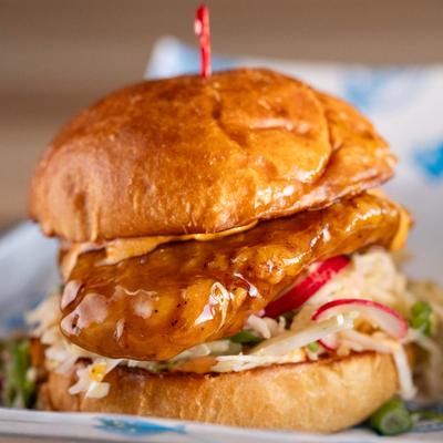 Fried chicken sandwich in orange sauce.