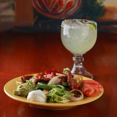 Grilled meat, mixed salad and dip on the side, cocktail in the back