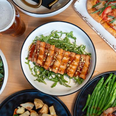 Sesame crusted hoisin pork belly served over a bed of greens, overhead view.