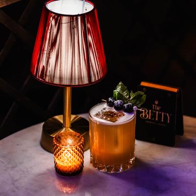 South Austin Sour on a table beside a lamp and a lit candle.