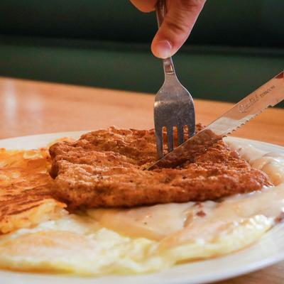 Chicken fried steak served with two fried eggs and hash browns
