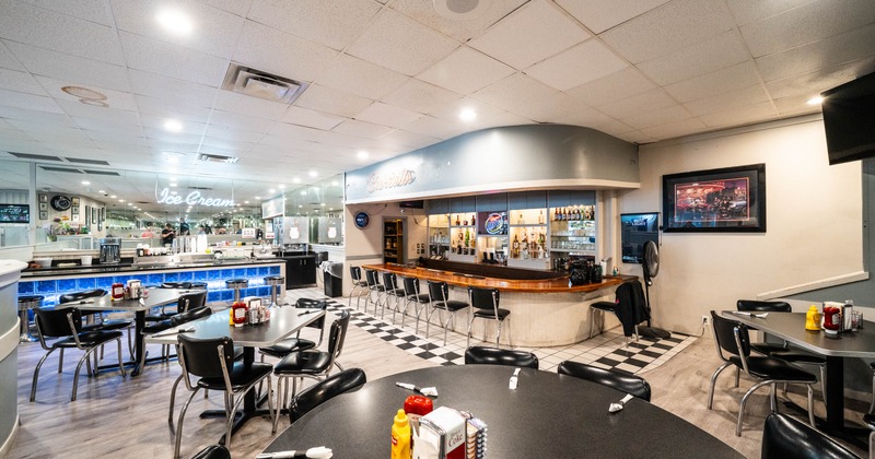 Interior, tables, chairs, a bar, and neon signage