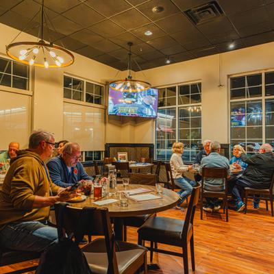 Interior with wooden tables and chairs, industrial-style lighting and people seated.