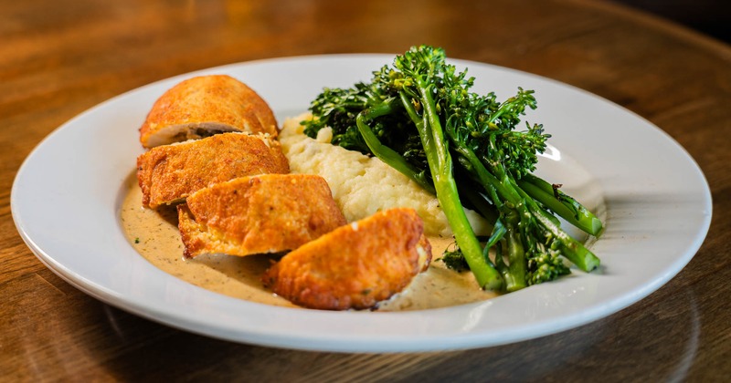 Stuffed Chicken on a plate with  mashed potatoes and broccolini