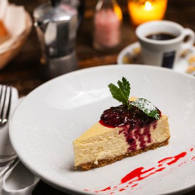 A slice of tiramisu topped with berry sauce and mint leaves.