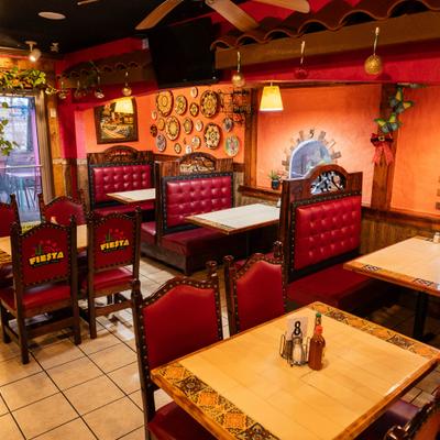 Restaurant interior with red leather booths, wooden tables, vibrant wall decor, hanging lights.