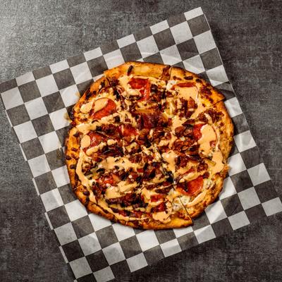Pizza with chicken breast, mozzarella, crispy bacon, tomatoes, and ranch dressing.