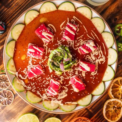 Tuna Tiradito dish on a wooden table with cocktails.