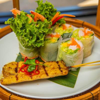 Appetizer platter with various fresh sping rolls and chicken satay.