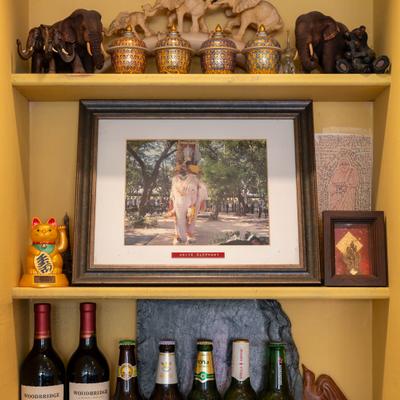 Wooden shelf featuring a combination of Thai decor and alcoholic beverages.