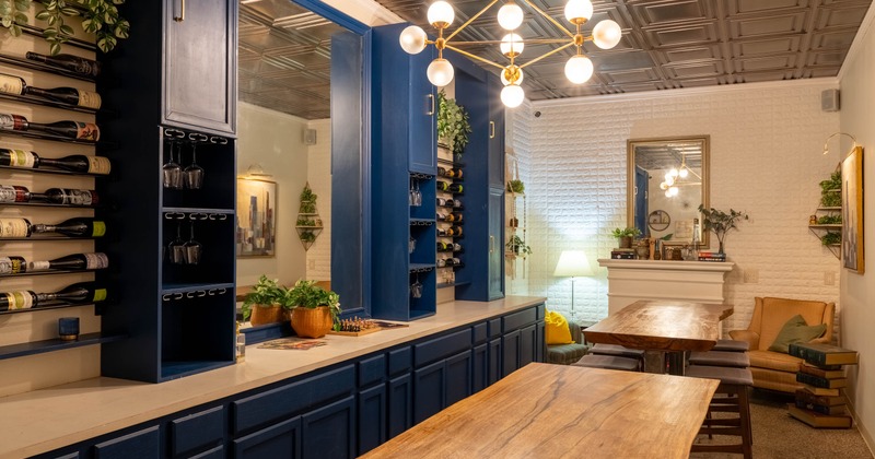 Interior with dark blue home bar, wine racks, wooden tables and cozy seating area