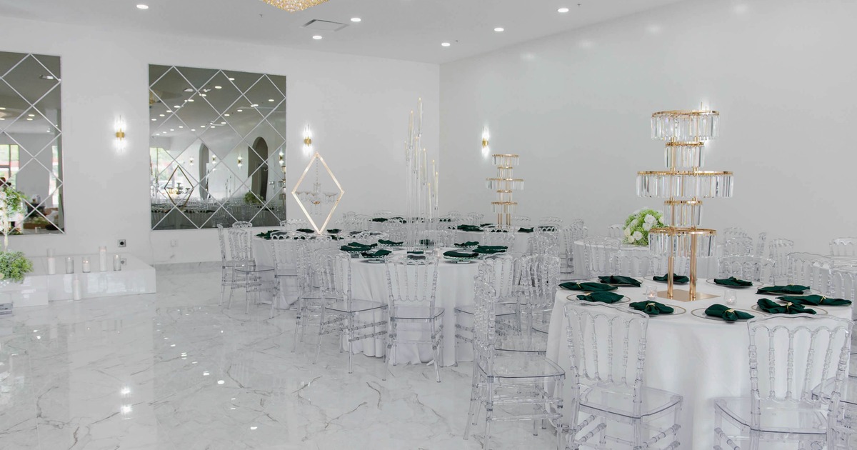 Elegant event hall, round tables, clear chairs and gold-tiered candle holders