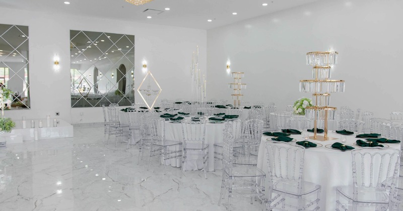 Elegant event hall, round tables, clear chairs and gold-tiered candle holders