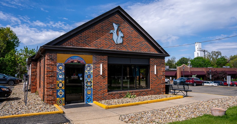 Restaurant brick building building featuring a tiled entryway mural and signage