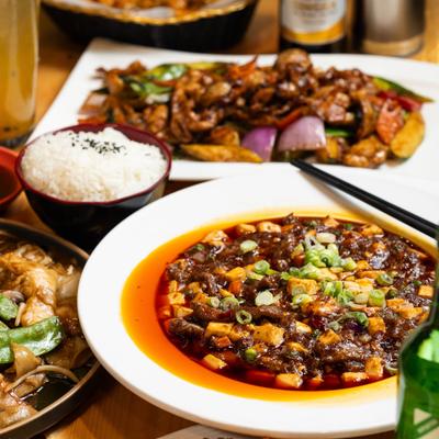 Spicy tofu stew served alongside rice and stir fry.