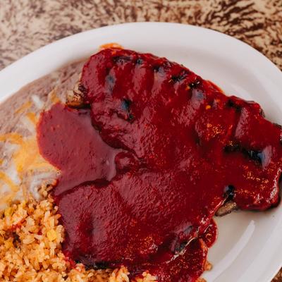 A plate of meat covered in red sauce and rice.