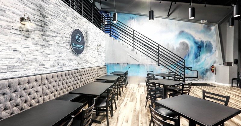 Interior, downstairs high back banquette seating by a wall with tables and chairs