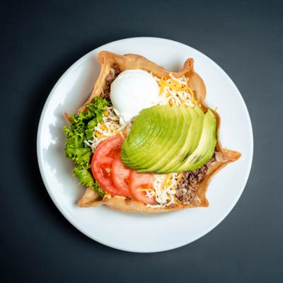 Taco salad with avocado, ground beef, tomatoes, and cheese.