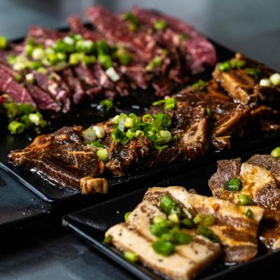 Raw and marinated cuts of Korean barbecue meats, garnished with green onions.