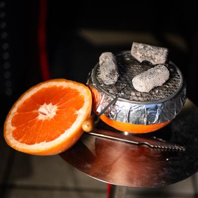Hookah bowl wrapped in foil, with charcoal cubes and a slice of grapefruit.