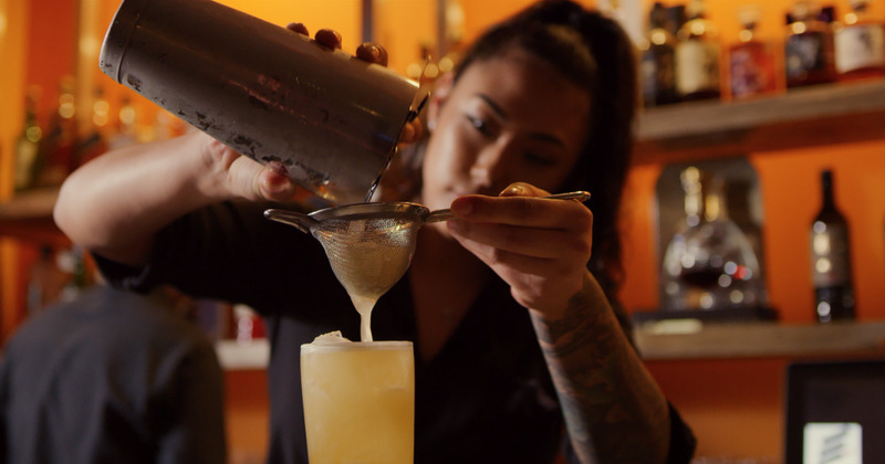 Bartender using shaker and sieve to pour a drink, closeup