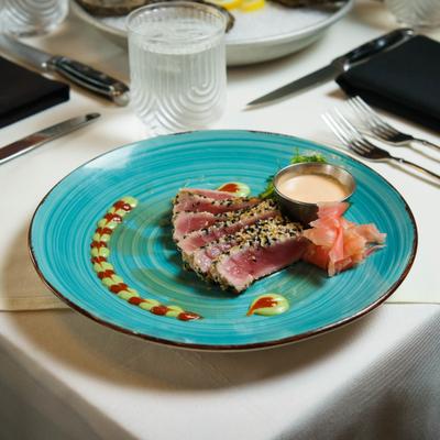 Seared tuna slices with sauce on a blue plate.