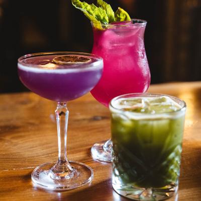 Assorted cocktail drinks on a wooden table.