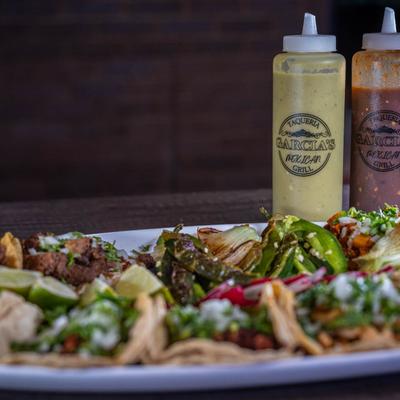 Tacos on a plate with condiments slightly behind.