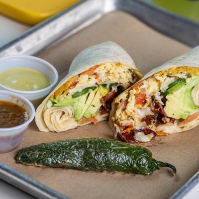 Breakfast burrito  served beside a roasted pepper and two cups of salsa.