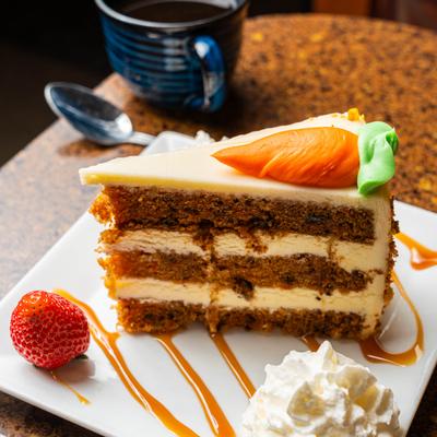 Carrot cake slice with cream frosting and whipped cream.