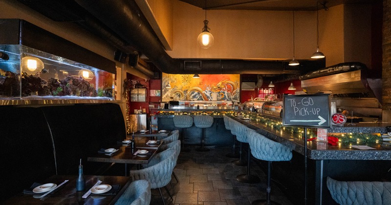 Interior with a sushi bar, tables, chairs, a fish tank and a To-Go Pick-Up sign