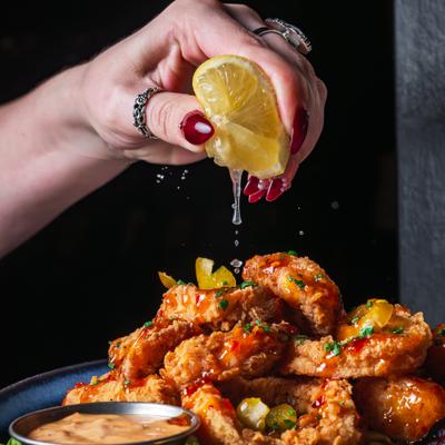 Lemon being squeezed over the plate of fried calamari.