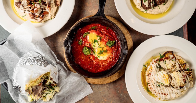 Table showcasing Mediterranean dishes including Shakshuka, Pita, Hummus