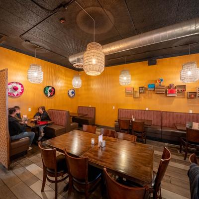 Interior with booths, wooden tables, orange walls, and bamboo pendant lights.