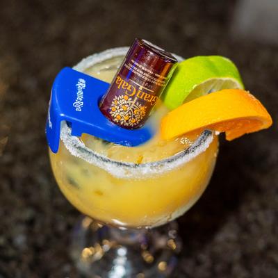 Texas margarita cocktail with small bottle of orange liqueur inserted into glass.