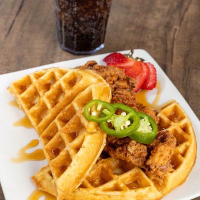 Chicken and waffles garnished with jalapenos and strawberries.