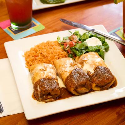 Three burritos, served with Spanish rice, salad, and sour cream.