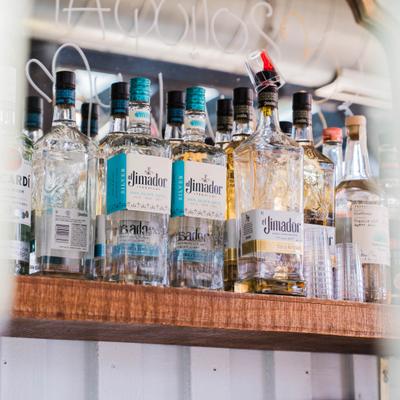 Multiple bottles of tequila displayed on a wooden bar shelf.