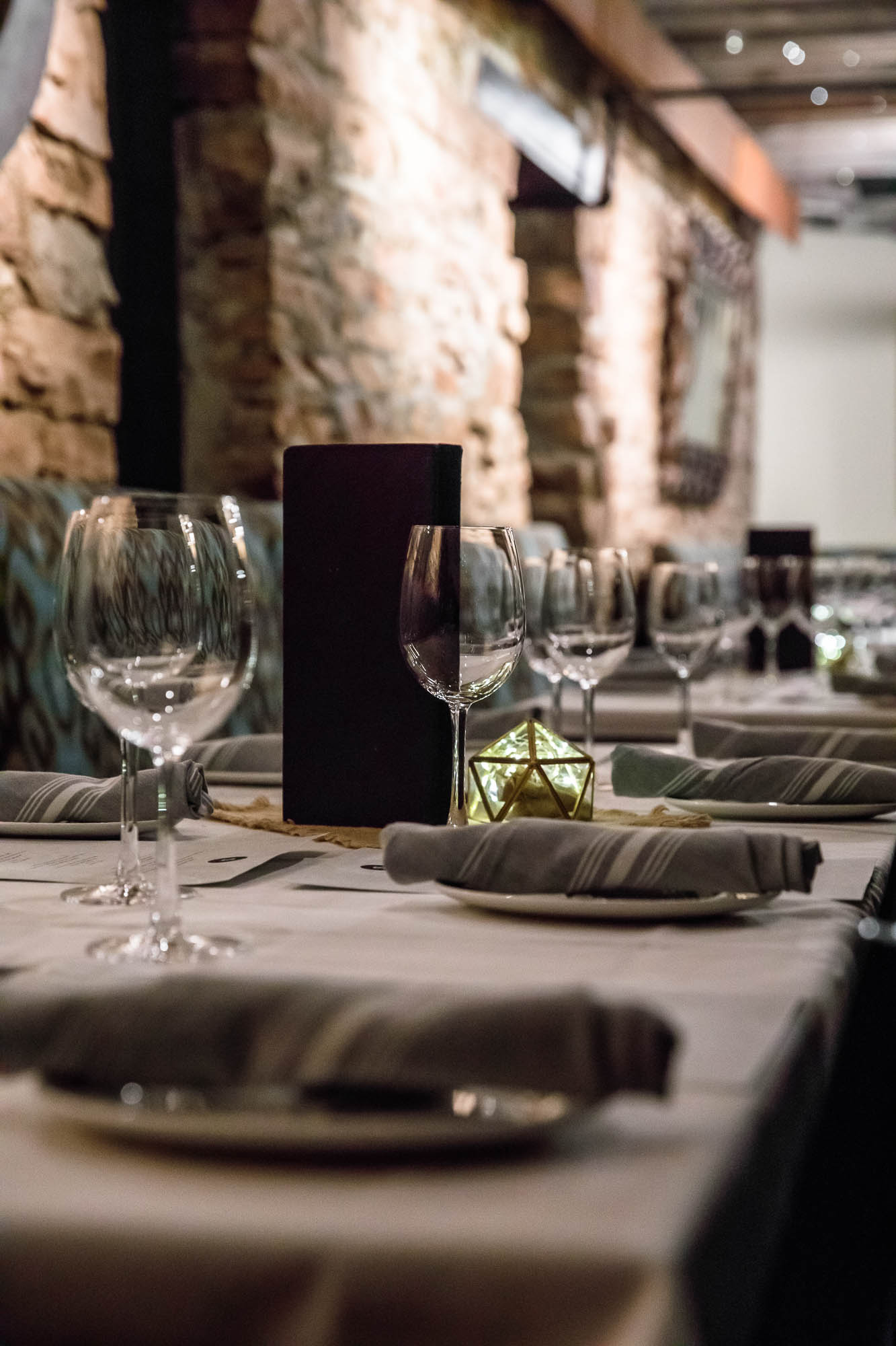 Cellar room, set dining tables decorated with greenery and lit candles