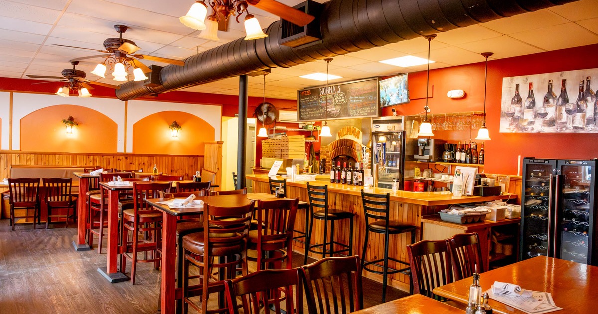Cozy interior, wooden tables, chairs, bar with high chairs, warm lighting, orange-red walls
