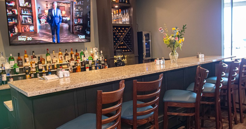 Interior, bar area, marble top bar with stools, large screen TV and drink shelves in the back