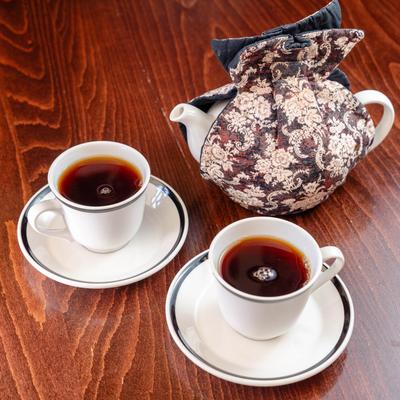 Two cups of tea with a teapot.