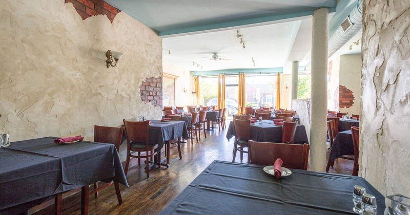 Rustic interior with dining tables covered with table cloths, tableware on the tables